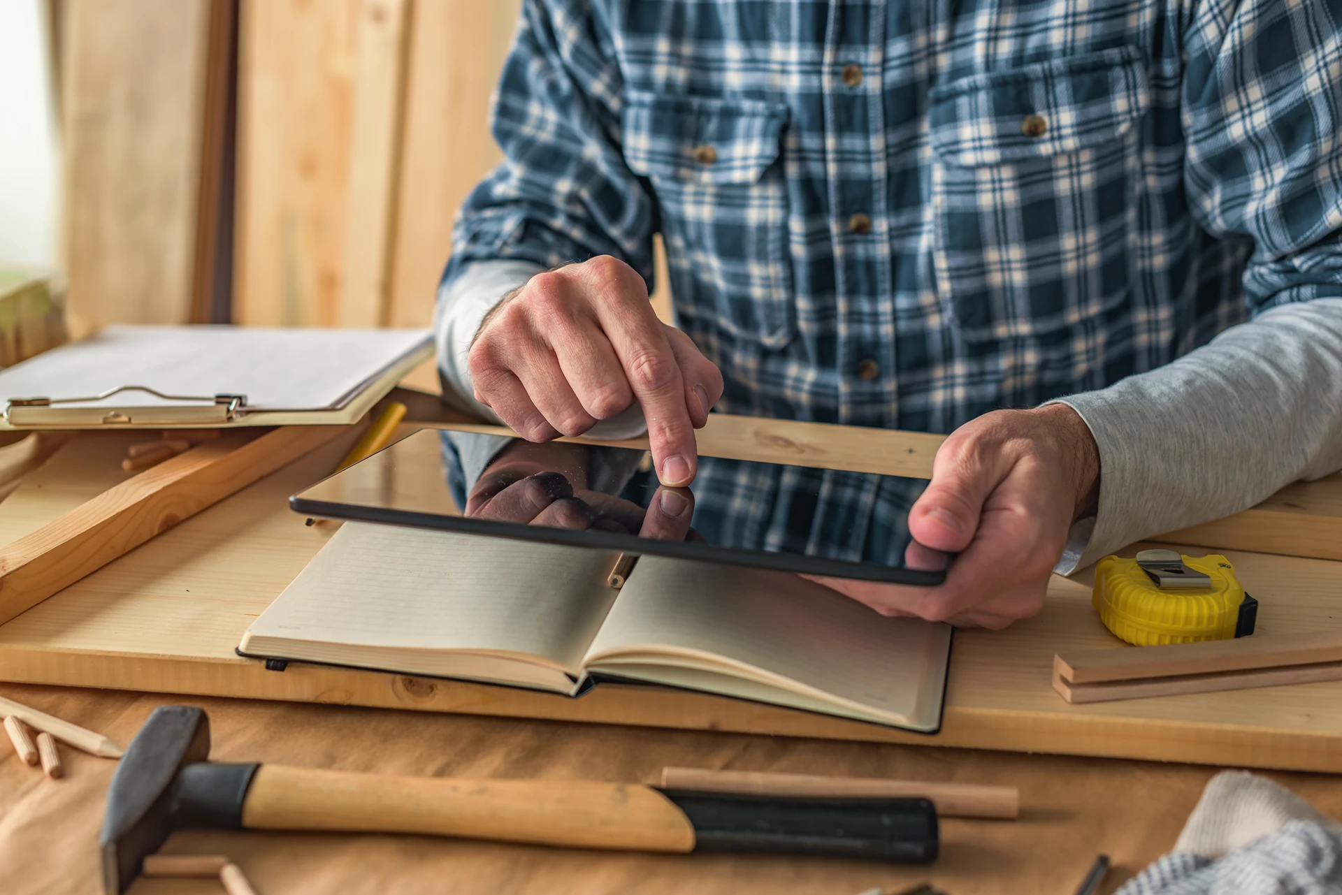 Un menuisier coche une tâche sur sa tablette dans son atelier